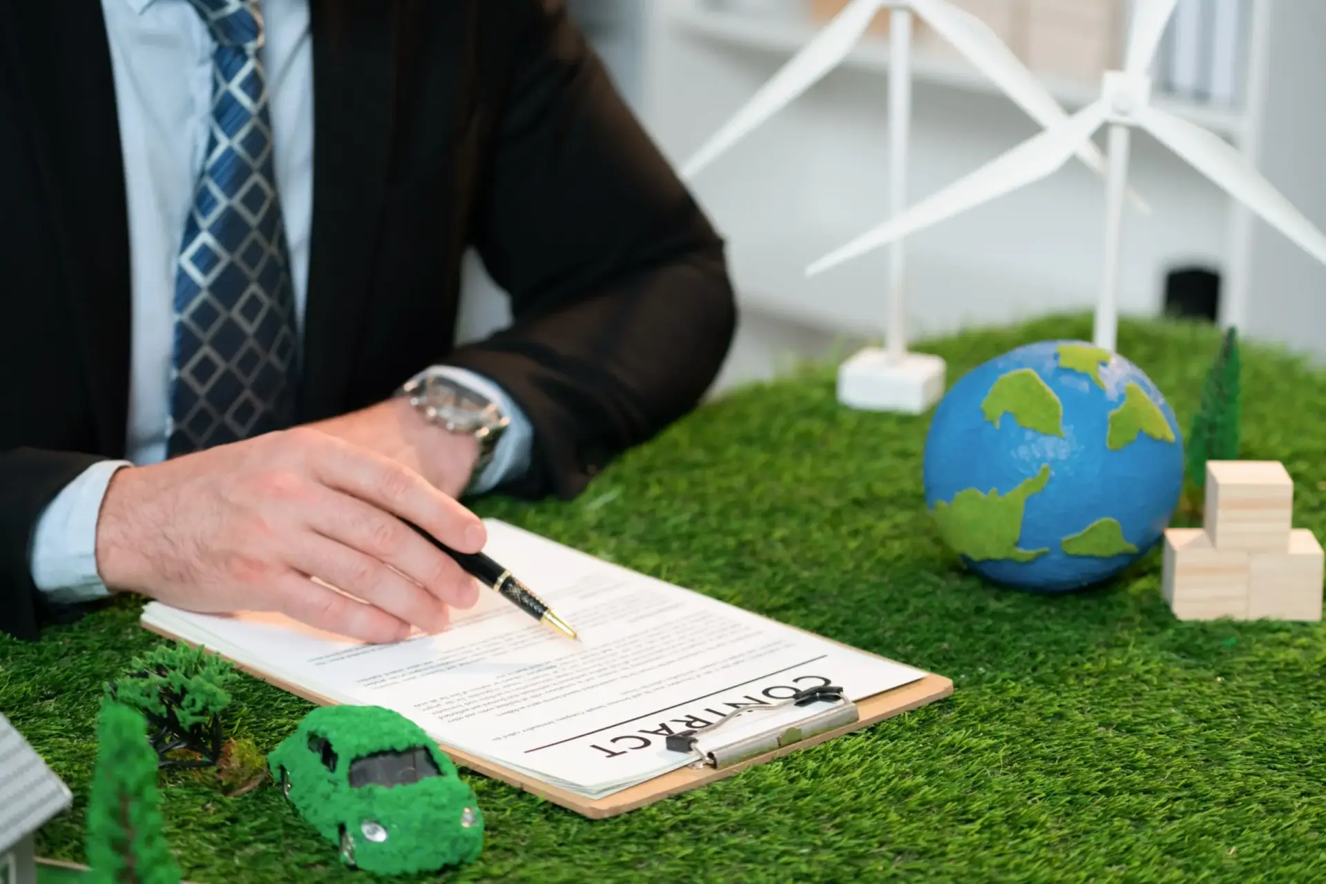 An adviser reviewing a document beside a model wind turbine and globe